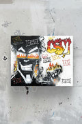 A rectangular graffiti art print featuring a stylized black and white face with red and yellow flame details, displayed against a textured gray concrete wall.